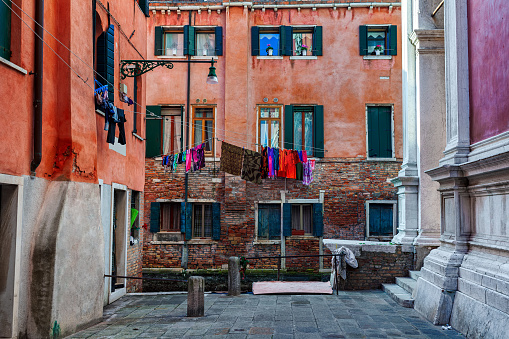 Small square surrounded by typical colorful houses with laundry on windows in Venice, Italy.