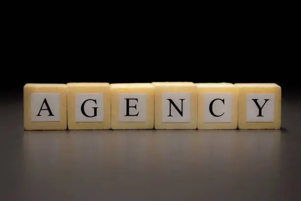 Photo of The word AGENCY written on wooden cubes isolated on a black background...