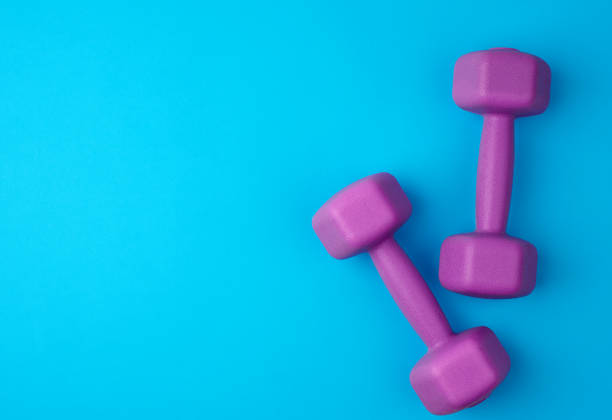 istock pair of purple plastic dumbbells on a blue background, 1208809608