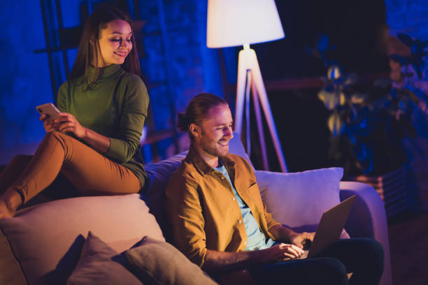 istock Nice attractive lovely cheerful cheery married spouses wife husband sitting on divan using device gadget spending free spare time hobby at home house apartment indoors 1208809930