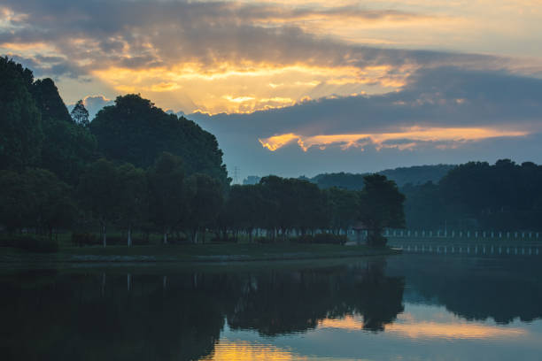 Sunrise over the rainforest lake around the Putra Square at the Malaysian government city Putrajaya, Malaysia. Beautiful Sunrise over the Putrajaya Lake and the trees with the typical morning haze