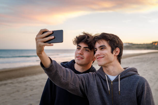 istock Two young boys making a selfie with the smart phone at sunset on the beach 1208810153