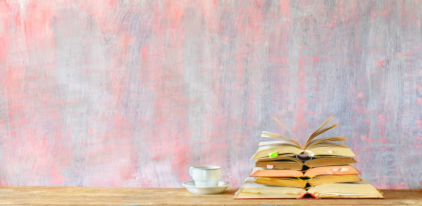 istock Stack of open books, cup of coffee, panorama format with copy space. Reading, education, literature, learning, book fair concept or mock up 1208810368