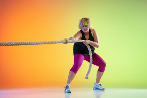 istock Young caucasian plus size female model's training on gradient orange background 1208812223