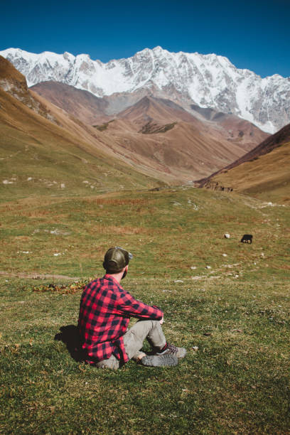 istock A man sits on the grass and enjoys the snow-capped mountains in the fall 1208812836