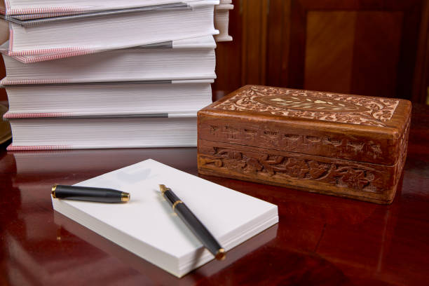 Wooden table with a notepad and a pen, a metal tray and a wooden box