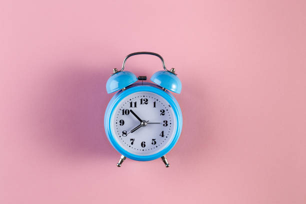 istock Blue vintage alarm clock on light pink color background 1208820725