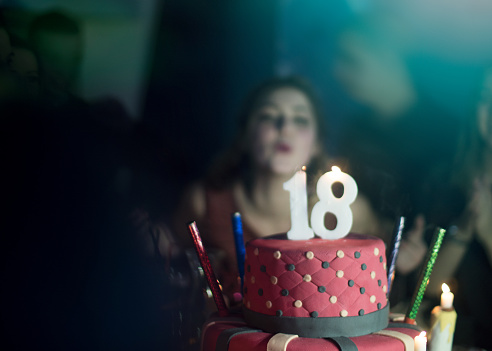 Girl celebrates the eighteenth birthday, blowing candles