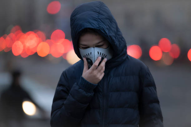 jeune personne utilisant le masque anti-pollution, air pollué, rue de ville - antipollution photos et images de collection