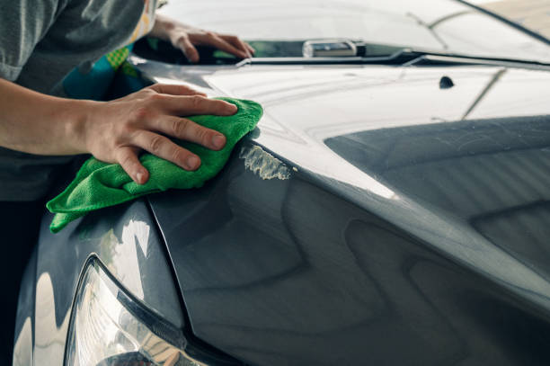 Man cleaning scratch on car with microfiber cloth and cleaner remover Man cleaning scratch on car with green microfiber cloth and cleaner remover waxing stock pictures, royalty-free photos & images