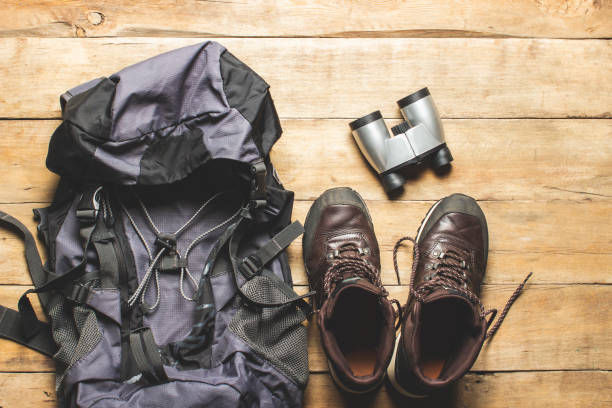 istock Boots for trail, backpack, binoculars, camping equipment on a wooden background. The concept of hiking, tourism, camp, mountains, forest. Banner. Flat lay, top view 1208828461