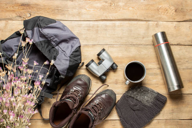 istock Boots for trail, backpack, binoculars, camping equipment on a wooden background. The concept of hiking, tourism, camp, mountains, forest. Banner. Flat lay, top view 1208828584