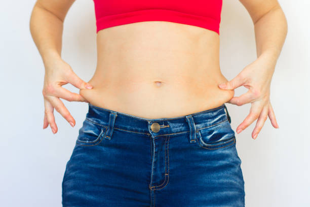 the fat female hands show excessive fat on the abdomen and waist. liposuction and fitness. the fat female hands show excessive fat on the abdomen and waist. liposuction and fitness. The concept of a healthy lifestyle and diet. pot belly stock pictures, royalty-free photos & images