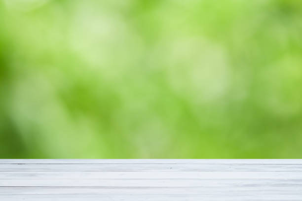 istock White wood table with green blurry trees background 1208828976