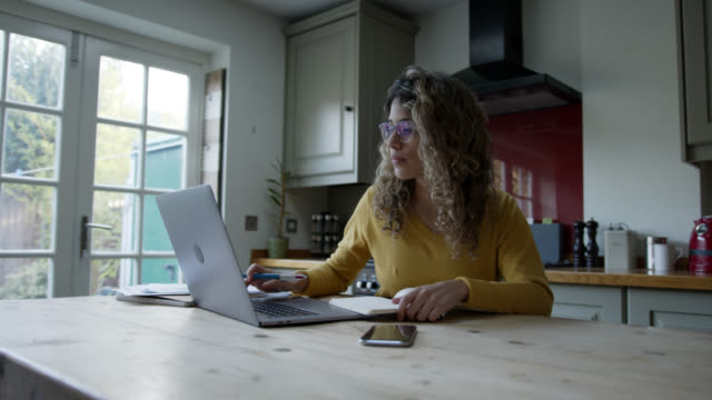 Mujer con centrada en América Latina que trabaja desde casa usando computadora portátil y bloc de notas photo