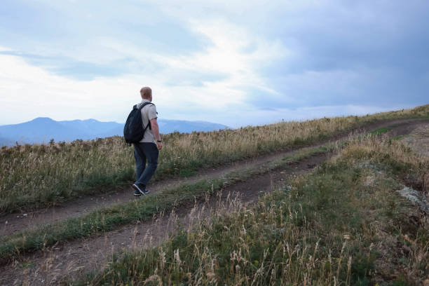 istock Man walks up the hill towards the dark sky 1208834846
