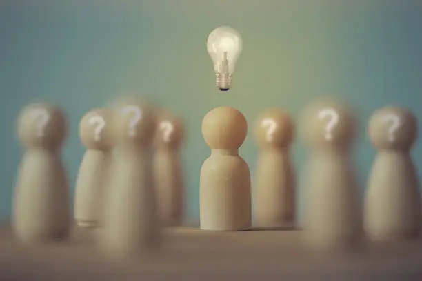 Photo of Creativity and development of innovation / Idea concept: Wood figures of people stand with Light bulbs glowing and question mark symbol. management human resource and encourage employees to have skill