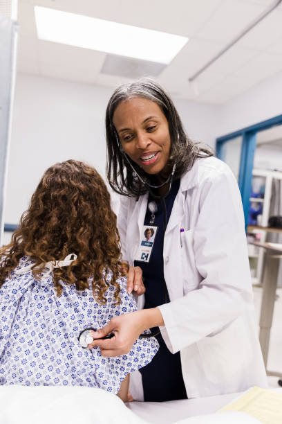 istock Mature female doctor uses stethoscope to check teen's lungs 1208837596