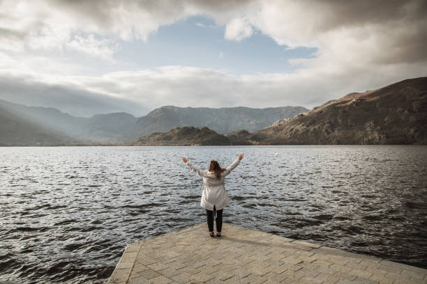 istock Young woman with arms raised by a lake 1208839420