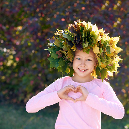 Autumn young girl portrait. Beauty female fall lifestyle. Leaves colorful wreath. Happy emotions. Kid model.