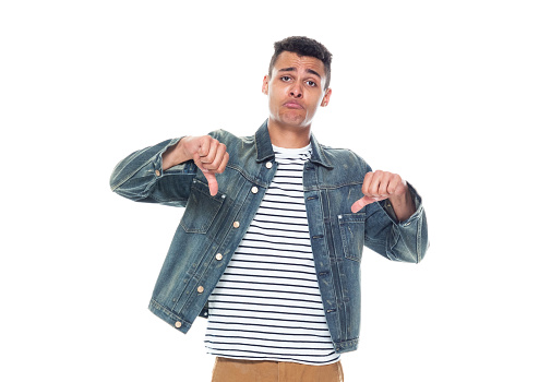 One person of aged 20-29 years old who is tall person with curly hair african-american ethnicity young male standing in front of white background wearing denim jacket who is disappointed and showing thumbs down
