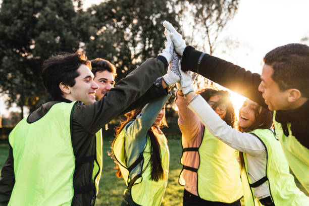 Volunteers celebrating together with high five at sunset. Multi ethnic group of adolescents.