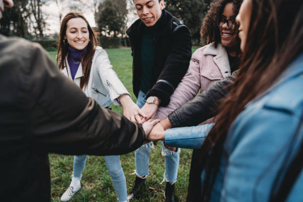 istock Group of friends stacking hands together outdoor, showing unity 1208839916