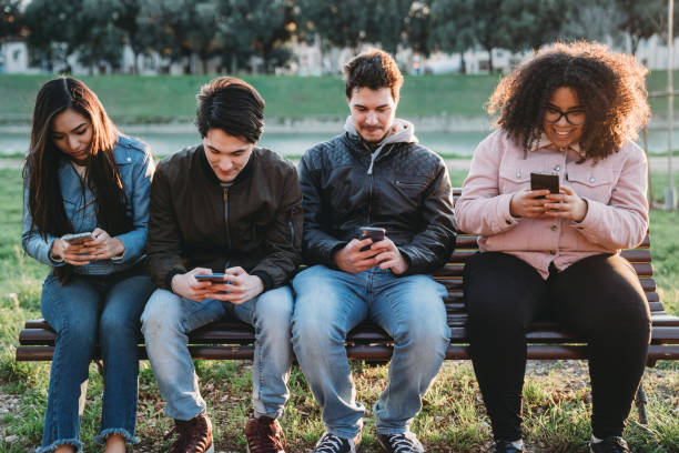 istock Multi ethnic group of adolescent friends using smartphones outdoor 1208841114