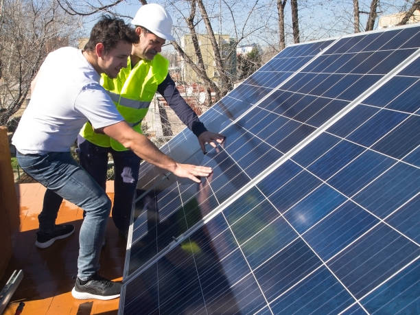 Caucasian seasoned technician showing the solar panels to his young client stock photo