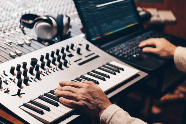 istock music producer hands composing a song on synthesizer keyboard and laptop computer in recording studio 1208841878