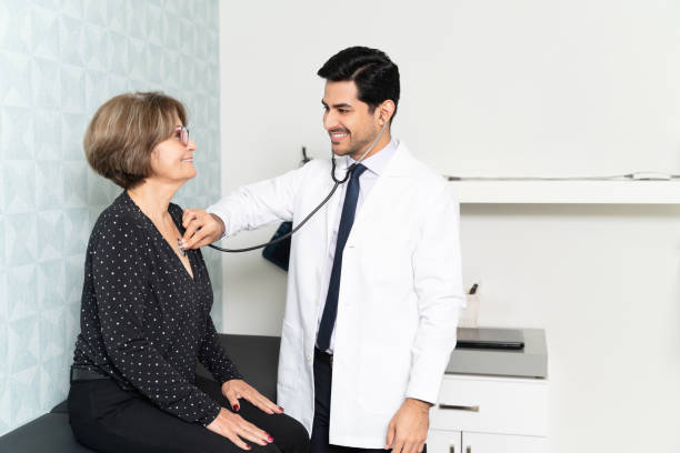 smiling physician examining patient in hospital - doctors office examination room examination table office imagens e fotografias de stock