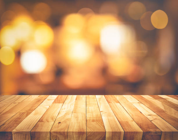 istock Wood texture table top (counter bar) with blur light gold bokeh background 1208843482