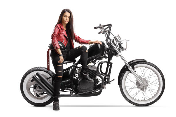 Young woman holding a helmet and sitting on a custom motorcycle isolated on white background
