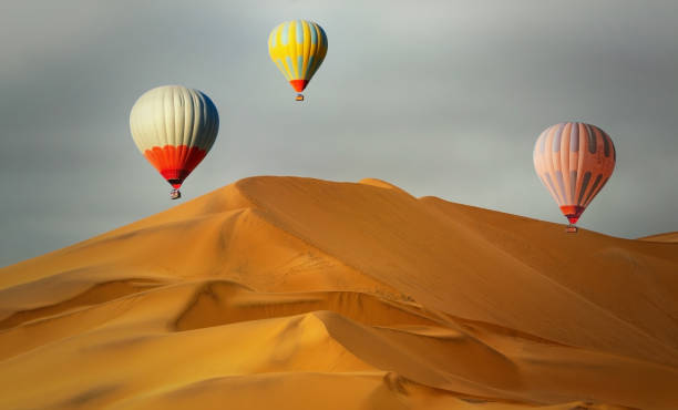 istock Colored hot air balloons flying over the sand dunes at sunset 1208844840