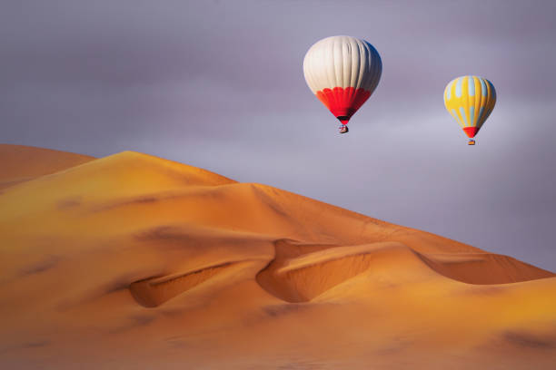 istock Colored hot air balloons flying over the sand dunes at sunset 1208844977
