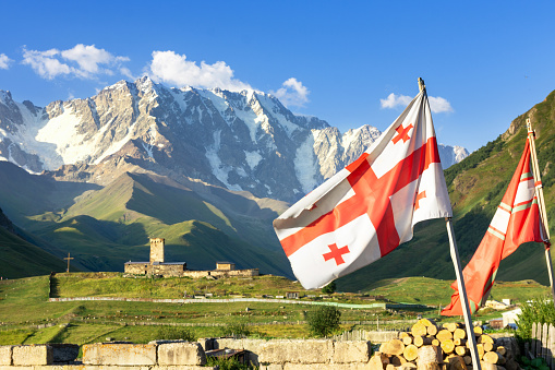 Georgia flag against the background of the Caucasus Mountains, Georgia's highest mountain in the background, Europe's hottest community Ushguli, Svaneti, Caucasus, Georgia