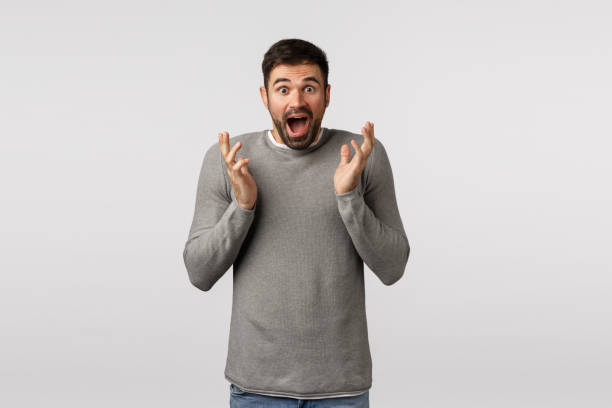 istock Impressed and excited man receive great news. Speechless ecstatic good-looking bearded guy in grey sweater realise he won, clasping hands cant believe own luck, feeling happy and surprised 1208846763