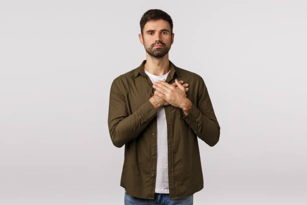 istock Devoted and courageous, dedicated young bearded man, press hands on heart and look camera, express loyalty and faith, listen national anthem, feeling moved or touched, white background 1208848807