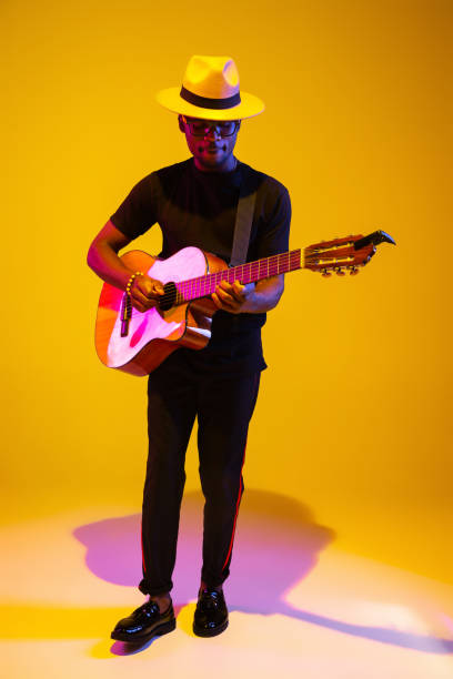 istock Young african-american musician singing, playing guitar in neon light 1208848903