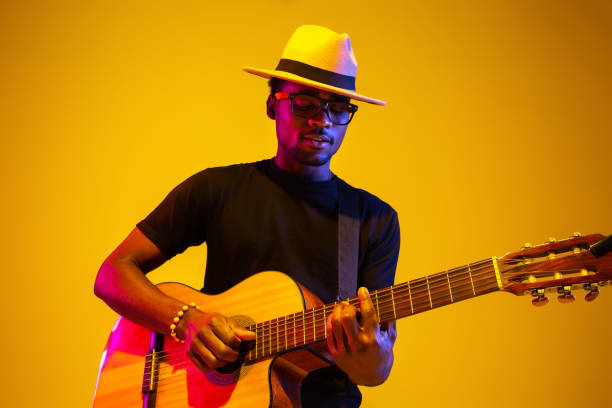 istock Young african-american musician singing, playing guitar in neon light 1208848928