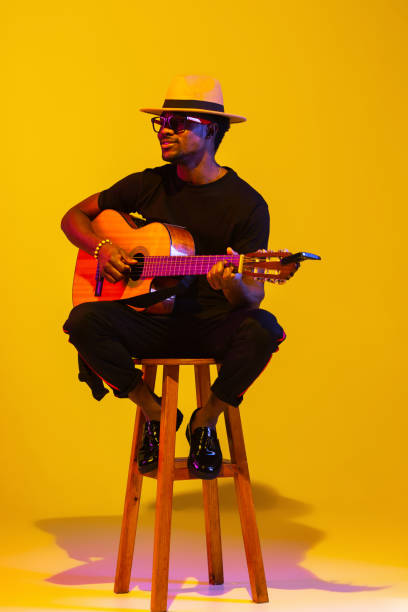 istock Young african-american musician singing, playing guitar in neon light 1208848932