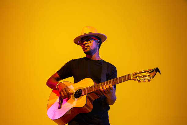 istock Young african-american musician singing, playing guitar in neon light 1208848943