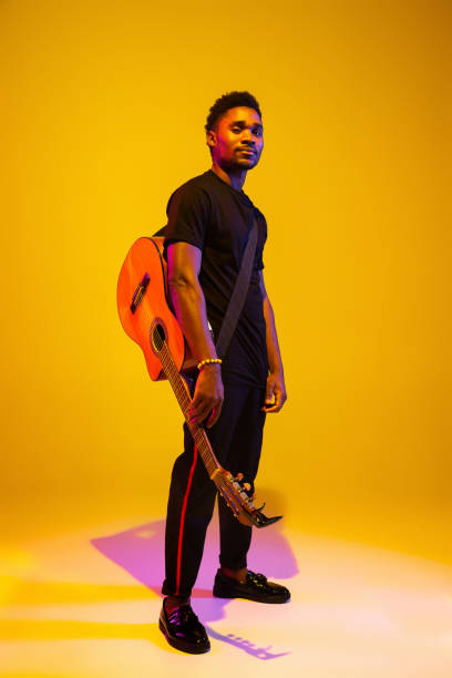 istock Young african-american musician singing, playing guitar in neon light 1208848953