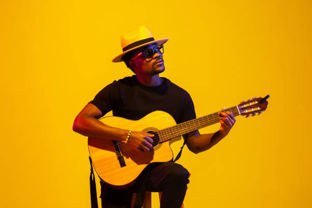 istock Young african-american musician singing, playing guitar in neon light 1208848983
