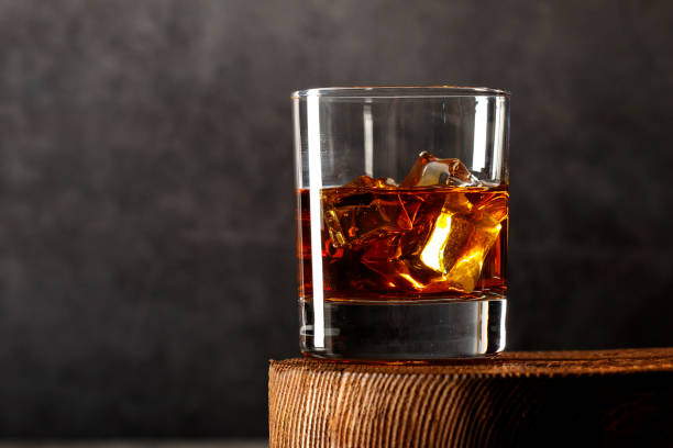whiskey with ice or brandy in a glass on a rustic background. whiskey with ice in a glass. whiskey or brandy. selective focus. - cigar whisky bar cognac imagens e fotografias de stock