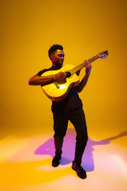 istock Young african-american musician singing, playing guitar in neon light 1208849044