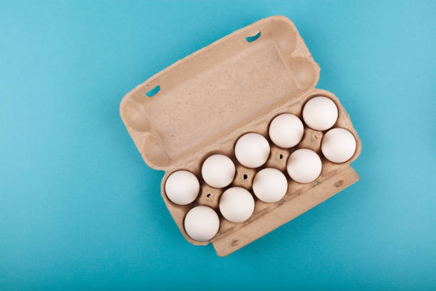 istock Egg Chicken eggs. Top view of an open gray box with white eggs. Isolated on a blue background. The concept of a healthy lifestyle, getting pure protein. Proper Breakfast. Ten eggs 1208852516