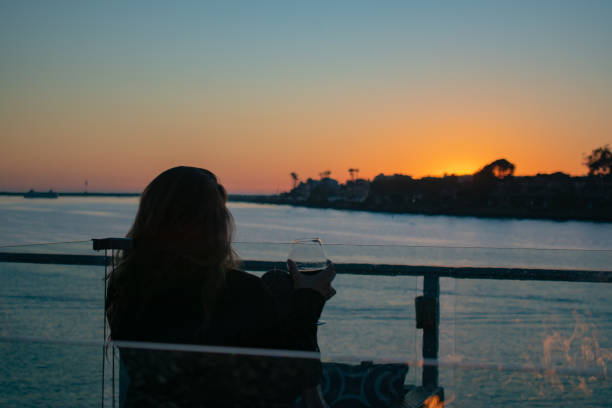 istock Young woman watching sunset over water with fire pit 1208854937