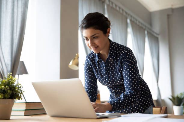 istock Smiling Indian woman working on laptop at home 1208855980