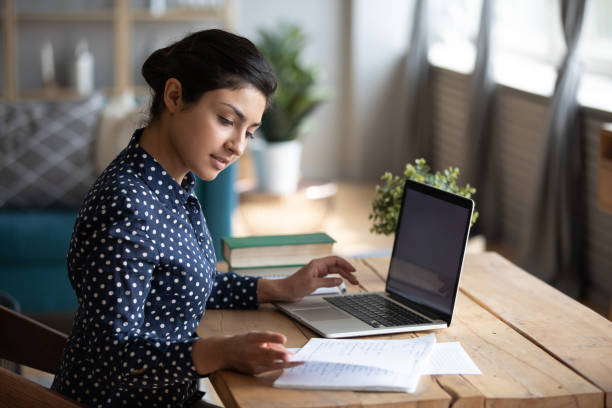 Millennial Indian girl study at laptop making notes Millennial Indian girl sit at desk in living room study on laptop making notes, concentrated young woman work on computer write in notebook, take online course or training at home, education concept teen wishing stock pictures, royalty-free photos & images